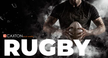 Man in black rugby jersey holding a rugby ball with the word ruby written in white at the bottom of the image