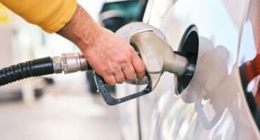 Hand holding a fuel pump busy refueling a car.