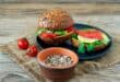Homemade organic salmon burgers with tomato, corn salad and avo