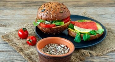 Homemade organic salmon burgers with tomato, corn salad and avo