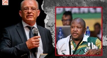 Man in suit with microphone in hand on left. Man with ANC shirt and ANC flag in background on right