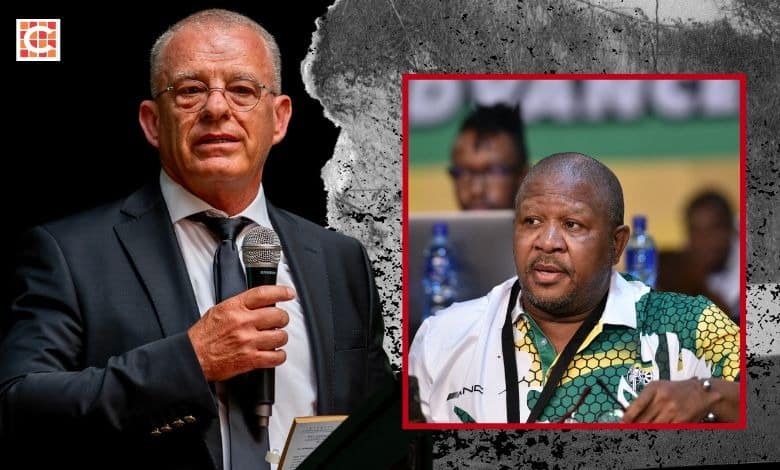 Man in suit with microphone in hand on left. Man with ANC shirt and ANC flag in background on right