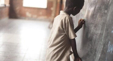 School boy writing on a black board
