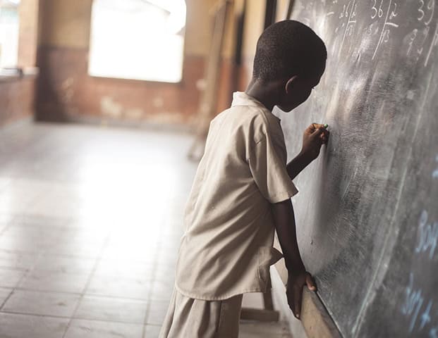 School boy writing on a black board