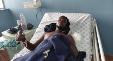 man giving the thumbs up while lying in a hospital bed