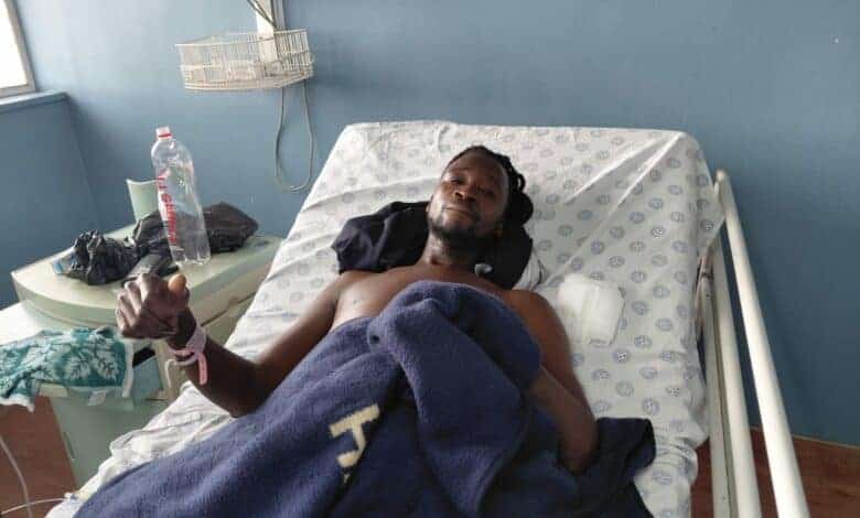 man giving the thumbs up while lying in a hospital bed