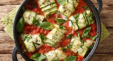 Baked zucchini rolls with ricotta cheese and herbs in tomato sauce