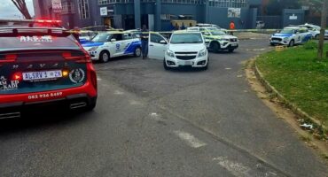 A street view with crime scene tape and various emergency vehicles visible