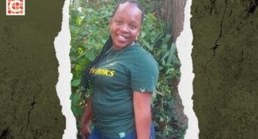 Woman with long braided hair standing in front of plants, posing for the camera wearing a green Springboks T-shirt.