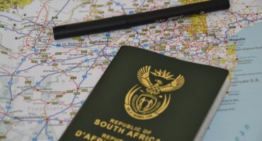 Image of a map with a South African passport and a pen lying on it.