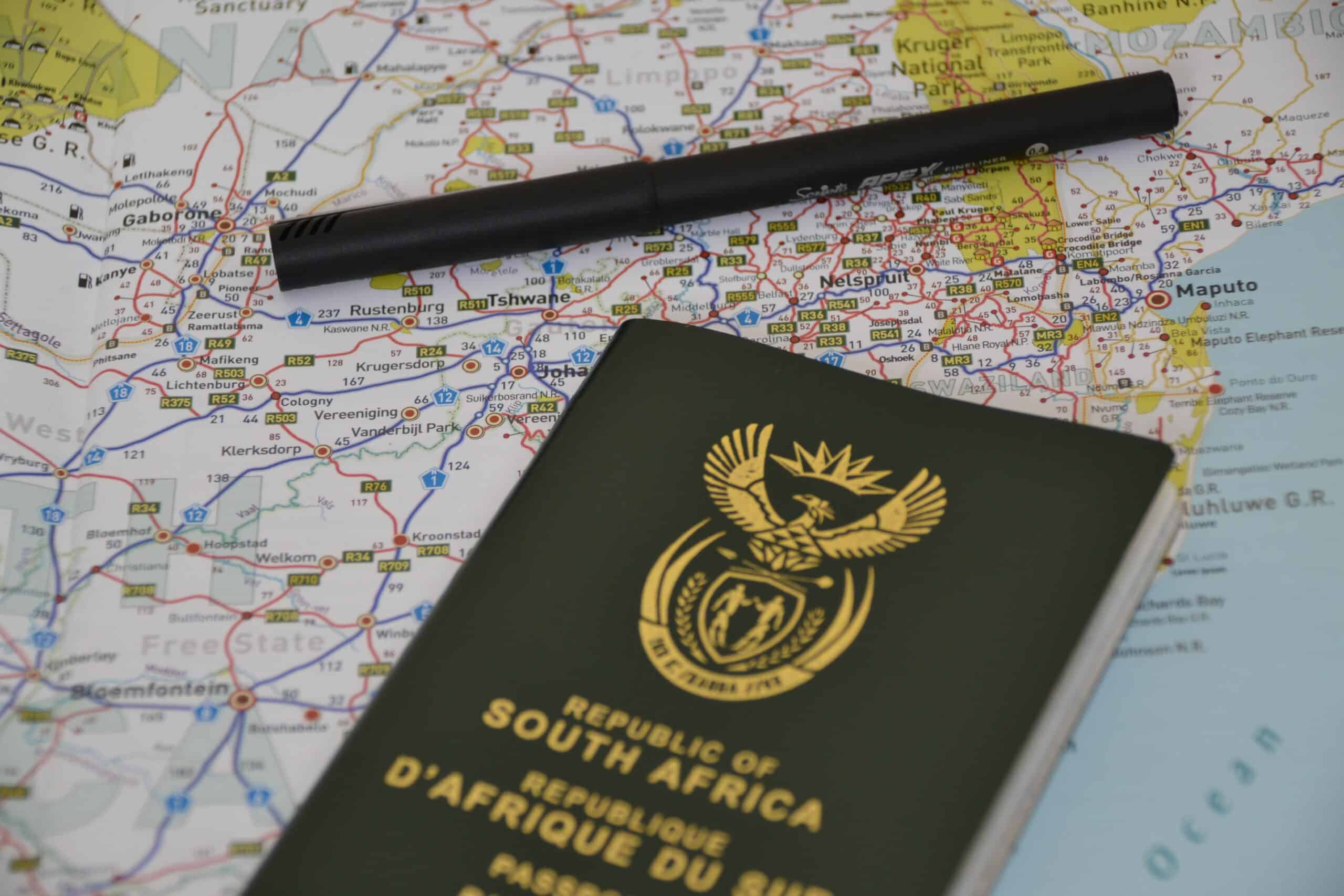 Image of a map with a South African passport and a pen lying on it.
