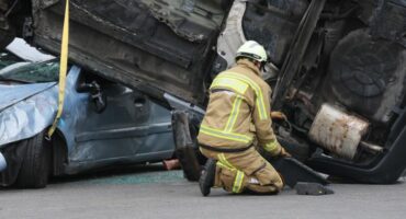 Fireman crouching in front of an accident wreckage.