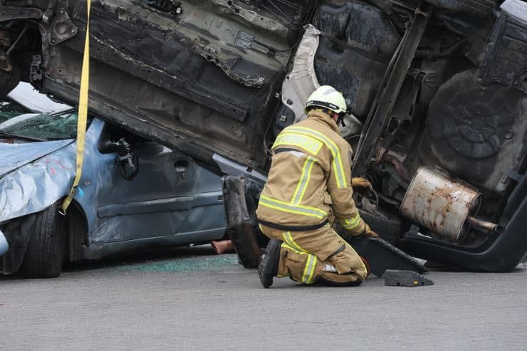 Fireman crouching in front of an accident wreckage.