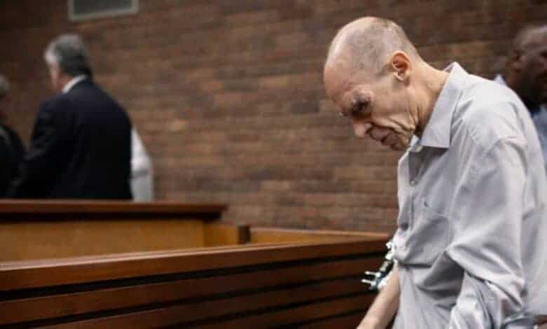 Bald man in court, appearing distressed and looking down.