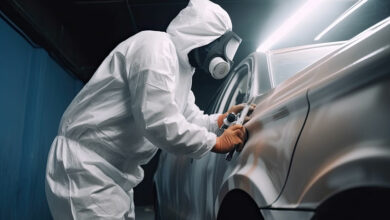 Car painter in protective clothes paints automobile with paint in chamber workshop. Generative AI