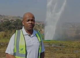 A man in a safety vest standing next to a water fountain.