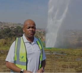 A man in a safety vest standing next to a water fountain.