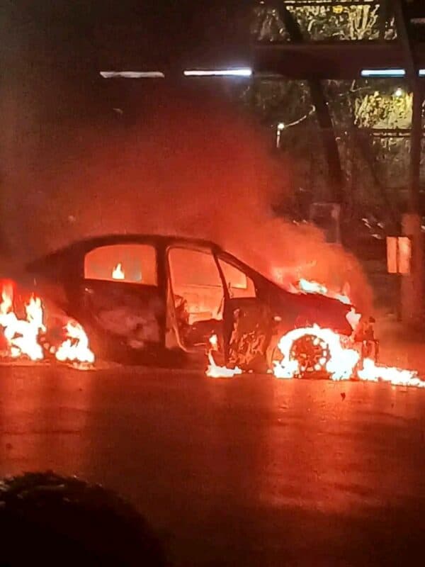 A violent assault on e-hailing vehicles has left one dead, two injured, and both cars destroyed by fire. Police are investigating possible taxi industry links.