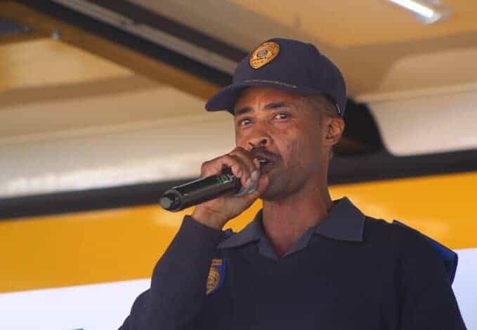 Police officer speaking at Soweto Urban community event, engaging residents and promoting safety awareness.