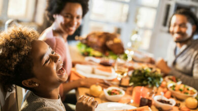 Cheerful African American girl with her parents at dining table.