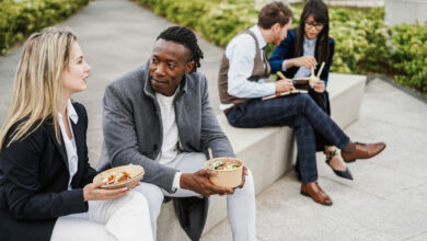 Multiethnic business people doing lunch break outdoor from office building - Focus on african man face