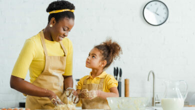 cute african american daughter looking at cheerful mother kneadi