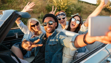 Happy young people taking selfie with smartphone in the car