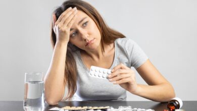 Young woman suffering from headache holding pills in her hand