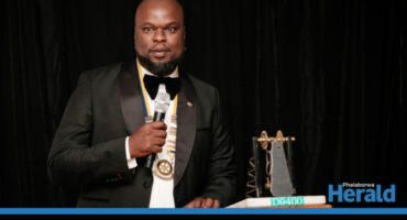 Thabiso Mkhombo, Phalaborwa Rotary Club president speaks at an event with a trophy next to him.