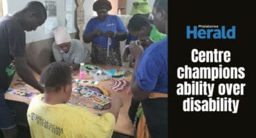 People work on arts and crafts at a table.