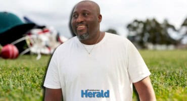 Mandla Mashimbyi with a blurred cricket hat and ball in the background.