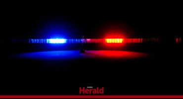 Blue and red police lights shine in the drak.