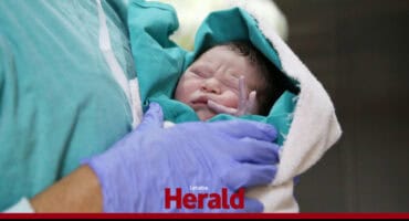 A doctor holds a newborn baby.
