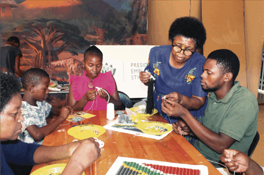 Learners and teachers crafting with beads.