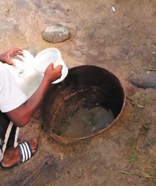 a water well collects water, a person can be seen next to the well with a bucket
