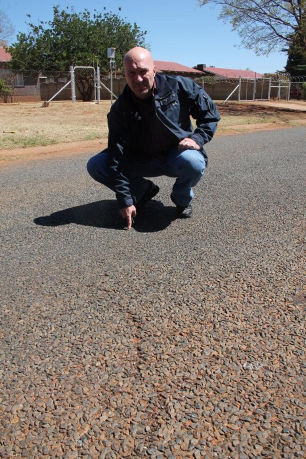 Mr Carlos Rebelo at the subsidence in the road. Some cracks can also be seen on the road surface.