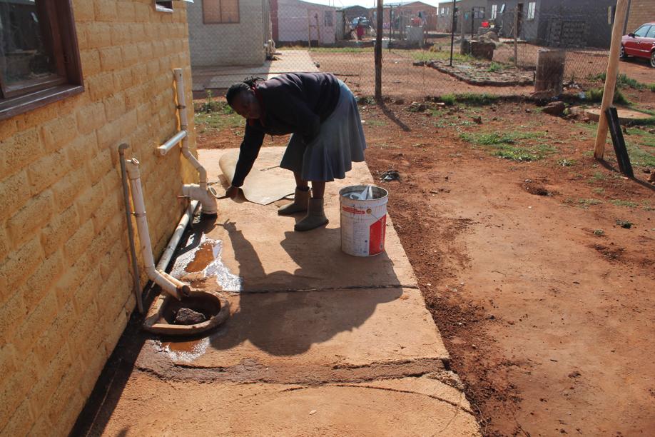 Ms Lebo Ramathibe shows where water has been leaking from the side of her house since she moved into it several months ago.