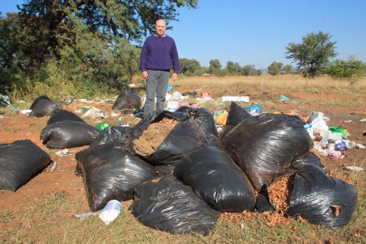 Mnr. Carlos Rebelo by van die swart sakke wat aan die kant van Coronationstraat gegooi is. 