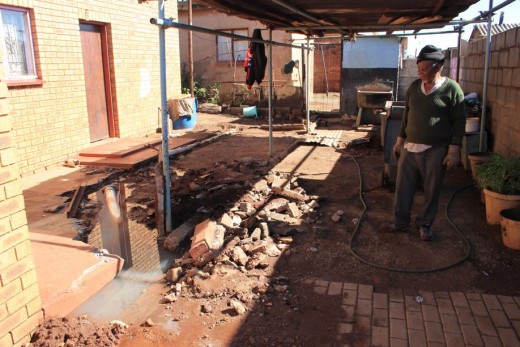 Mr Ben Kuaho shows how the pipe in his yard has burst after the municipal problems started.