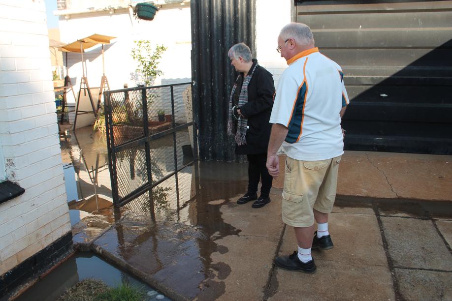 Mr George Melia and Ms Judy Rossouw at the Melia couple's flooded backyard.