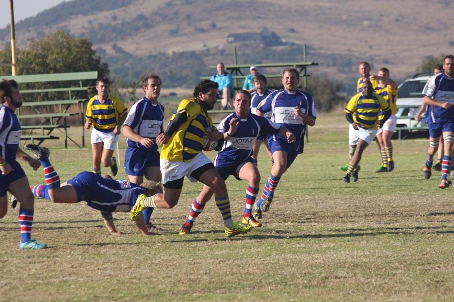 'n Speler van Fochville se tweede span besig om onder opponente van Lichtenburg uit te hardloop.
