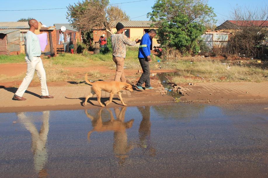 Extension 3 residents walking past one of the sewage leakages.