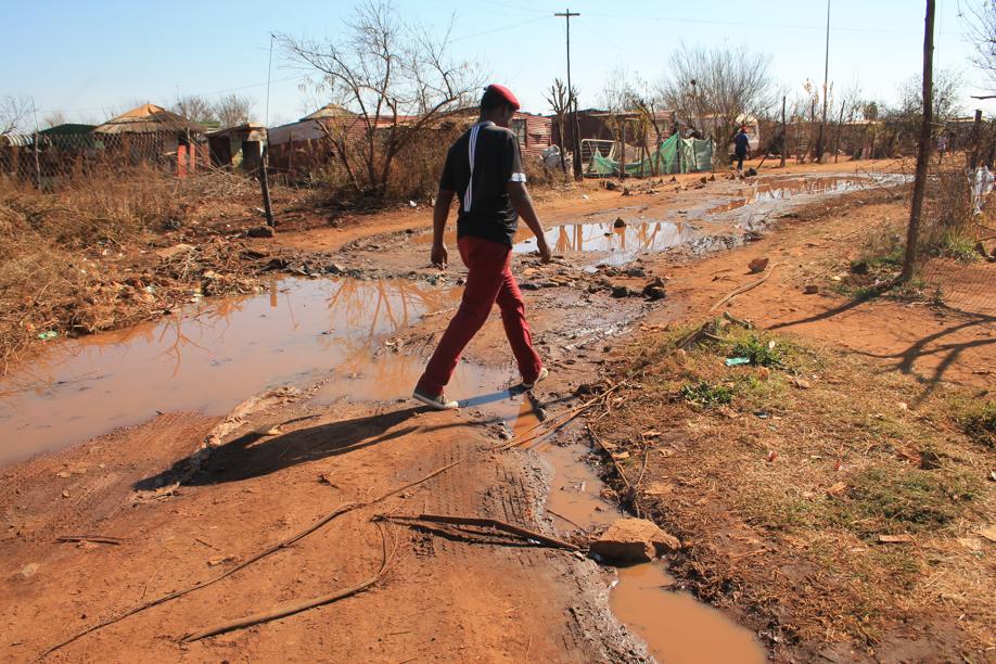 Mr Bizarre Mmowa making his way over sewage leakages with illegal electrical connections running through it.