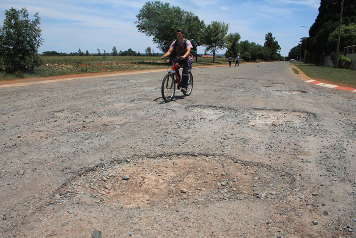 A cyclist rides past one of the huge potholes at the intersection of Lang and Andries streets.