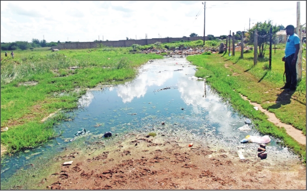 Mr Wilson Somali, a concerned resident, stands next to the dam of sewage.