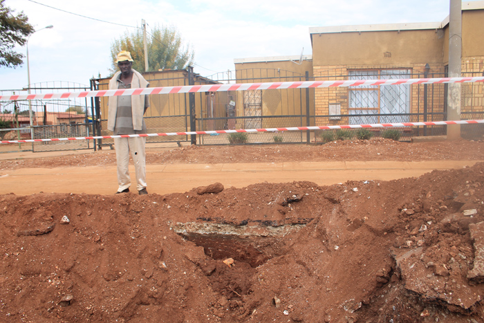 An angry resident stands alongside the brand new tar road that has been damaged by the contractors.
