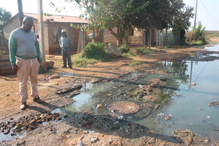 Messrs Lebohang Mangaliso and Johnny Lolo at the sewage leak in front of the houses.