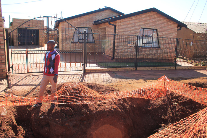 Mr Moeketsi Mogagale stands at the hole on the sidewalk in front of house No. 2337, left behind by the contractors on the sidewalk.