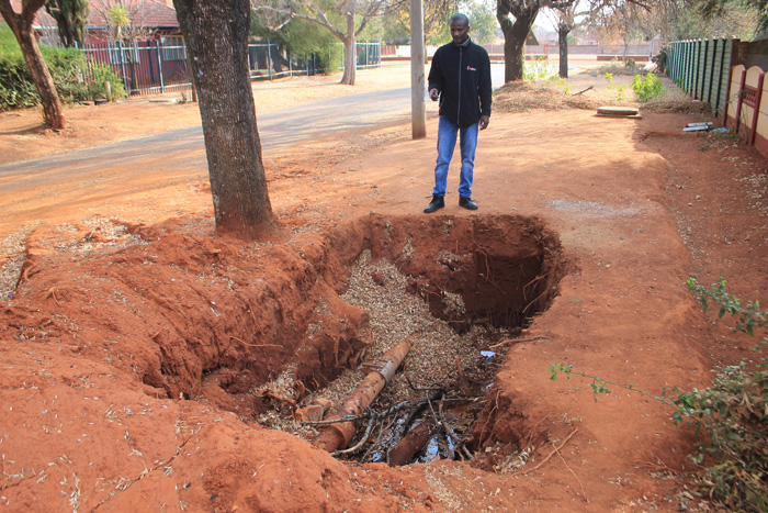 Mr Elias Mabilu at the huge hole that municipal workers left on the sidewalk in front of his house.