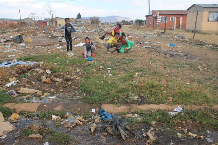 Children play on the vacant lot that is littered with filth.